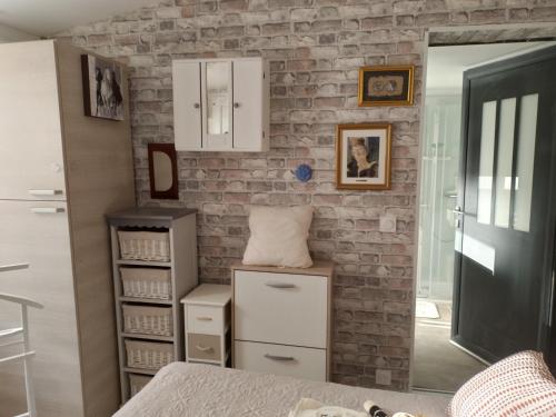 une pièce avec un mur de briques avec des armoires et des tiroirs blancs dans l'établissement Danyano, à Saint-Pierre-de-Chignac