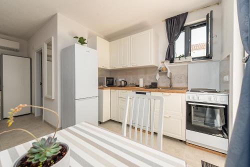 a kitchen with white cabinets and a white refrigerator at Apartment Varos with shared pool in Ugljan