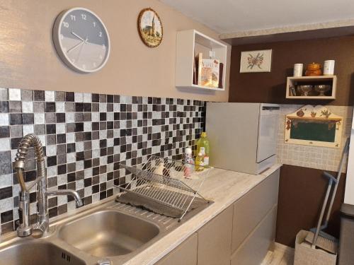 une cuisine avec un évier et une horloge murale dans l'établissement Danyano, à Saint-Pierre-de-Chignac