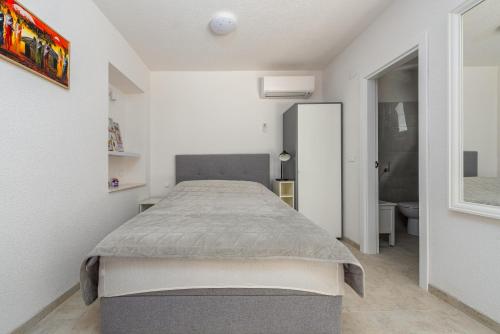 a bedroom with a bed in a white room at Apartment Varos with shared pool in Ugljan