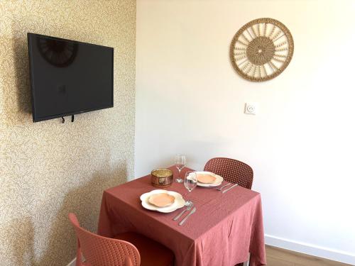 une table avec une nappe rouge et une télé dans l'établissement M113 Marquer Superbe T2 avec parking proche de la douane Moillesulaz et de Genève, à Gaillard