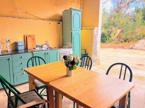 a kitchen with a wooden table with a vase of flowers on it at Organic Farmstay Glamping in St. Paul's Bay