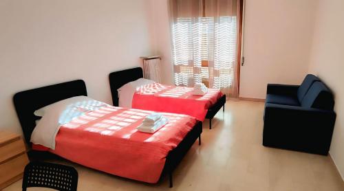 a bedroom with two beds and a blue chair at Golgi Archimede Casa in Pavia