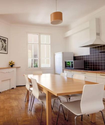 - une cuisine avec une table en bois et des chaises blanches dans l'établissement Appartement 5 pièces Cannes, à Cannes