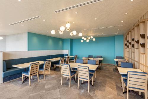 a dining room with tables and chairs and a blue wall at KAMENOI HOTEL Kujukuri in Asahi