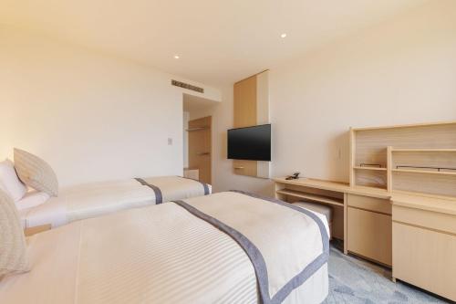 a hotel room with two beds and a television at KAMENOI HOTEL Kujukuri in Asahi