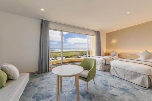 a hotel room with two beds and a table and a window at KAMENOI HOTEL Kujukuri in Asahi