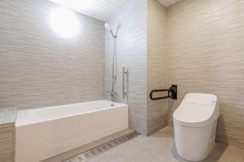 a white bathroom with a tub and a toilet at KAMENOI HOTEL Kujukuri in Asahi