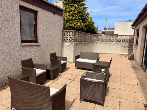 a patio with chairs and tables and a fence at Bright, Spacious 5-Bed, 4-Bathroom home on Loch Soy in Portsoy