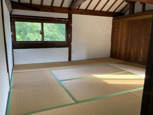 an empty room with a window in a house at ＰＥＮＳＩＯＮ　ＳＨＩＭＡＫＡＺＥ in Motobu