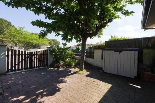 une clôture et un arbre à côté d'un trottoir en briques dans l'établissement Maisonnette au pied de l'Océan avec terrasse, à Biscarrosse