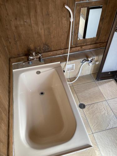 a bath tub in a bathroom with a sink at ＰＥＮＳＩＯＮ　ＳＨＩＭＡＫＡＺＥ in Motobu
