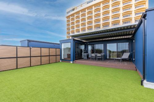 a house with a green lawn in front of a building at KAMENOI HOTEL Kujukuri in Asahi