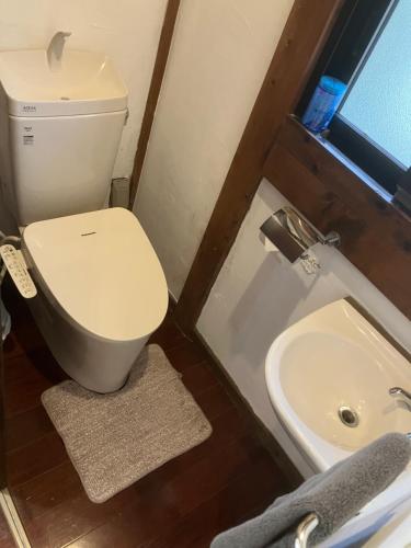 a bathroom with a toilet and a sink at ＰＥＮＳＩＯＮ　ＳＨＩＭＡＫＡＺＥ in Motobu