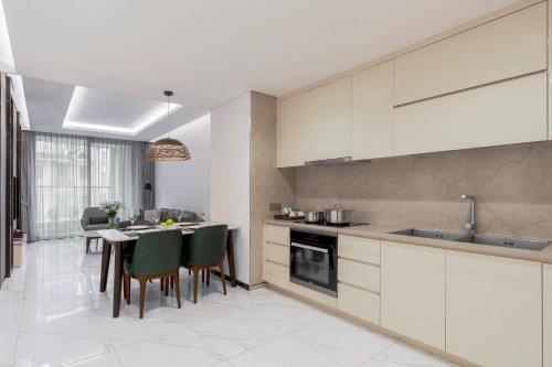 a kitchen with white cabinets and a table with green chairs at The Five Residences Hanoi in Hanoi
