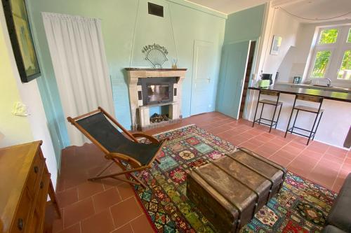 - un salon avec une chaise et une cheminée dans l'établissement La maison du gardien, à Sillé-le-Philippe