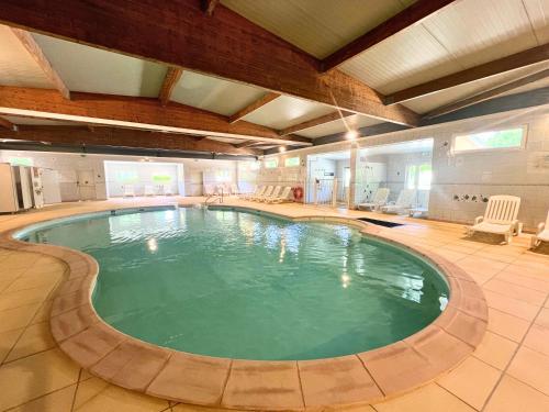 a large swimming pool in a large room with chairs at F011- Bungalow ensoleillé pour 4 proche EuropaPark in Boofzheim