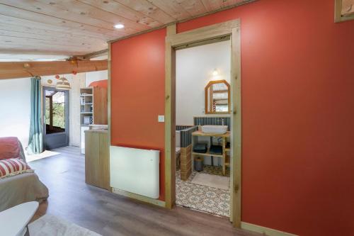a living room with a red wall and a doorway at Le Nid de Bluenn in Vosbles