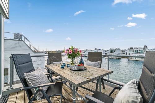 a table and chairs on a balcony with a view of the water at Ferienhaus Am Pier Olpenitz in Olpenitz