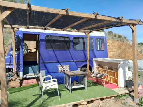 a blue van with awning and chairs and a table at PinoPerdido Olías Málaga in Málaga