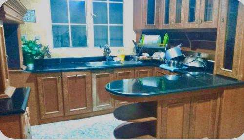 a kitchen with wooden cabinets and a blue counter top at Vila Princess Sentul Privatepool 6 bedroom,5bathroom, Tenis meja, billiard in Gadok 1