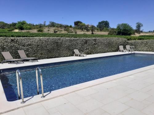 - une piscine avec 2 chaises à côté d'un mur dans l'établissement Petit gîte et Grande piscine, à Blauvac