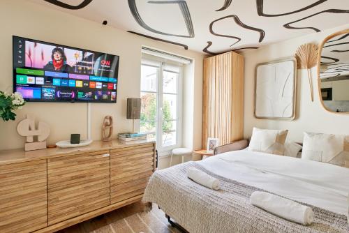une chambre avec un lit et une télévision au mur dans l'établissement Lepic studio, à Paris