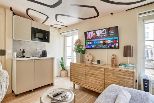 - un salon avec un canapé et une télévision au plafond dans l'établissement Lepic studio, à Paris