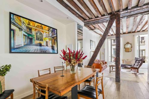 une salle à manger avec une table en bois et un tableau mural dans l'établissement Spacieux appartement au Coeur du Marais, à Paris