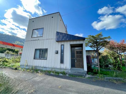 a small white building with a blue roof at 夕張ほっこり宿駅の前 in Yubari