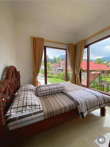 a bed in a room with a large window at Villa Kusuma Tawangmangu in Tawangmangu