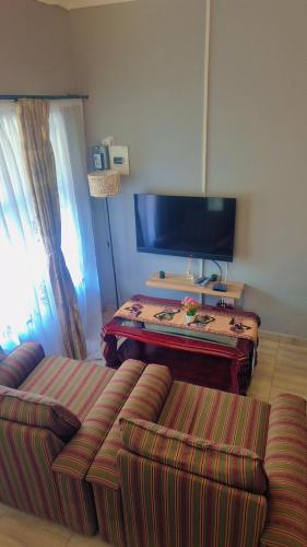 a living room with a couch and a flat screen tv at Little Haven! in Rustenburg