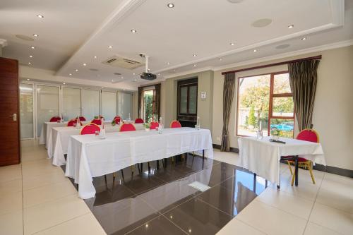a meeting room with white tables and red chairs at Tamboti Guest Lodge in Pretoria