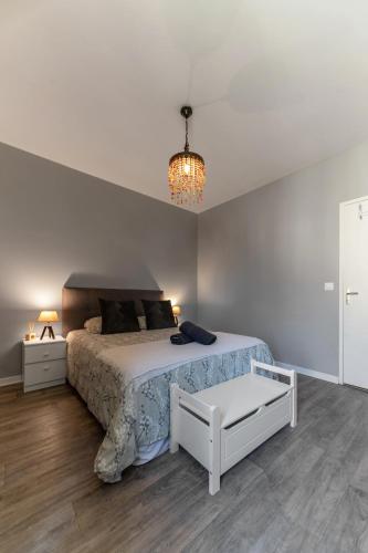 - une chambre blanche avec un lit et un lustre dans l'établissement L'Aromate - Grand Appartement Centre Ville, à Vichy