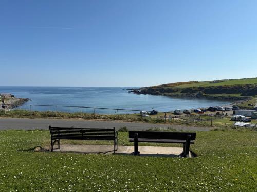 two benches sitting in the grass near a body of water at Bright, Spacious 5-Bed, 4-Bathroom home on Loch Soy in Portsoy