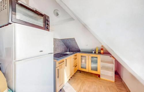 La cuisine est équipée d'un réfrigérateur blanc et de placards en bois. dans l'établissement Charmant appartement avec jardin à Schiltigheim, 30 m², à Schiltigheim