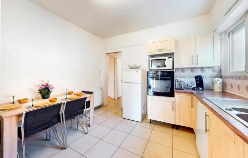 une cuisine avec des appareils blancs et une table avec des chaises dans l'établissement Appartement spacieux à Schiltigheim avec jardin, à Schiltigheim