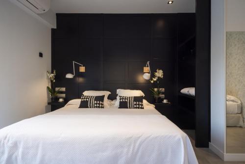 a bedroom with a large white bed with black walls at La Playa Suites Suances in Suances