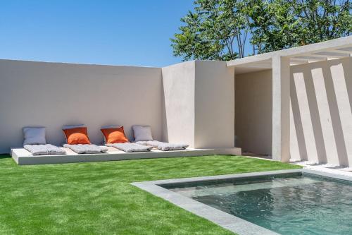 un jardin avec un banc avec des coussins et une piscine dans l'établissement Les Terrasses de l'Etoile, à Marseille
