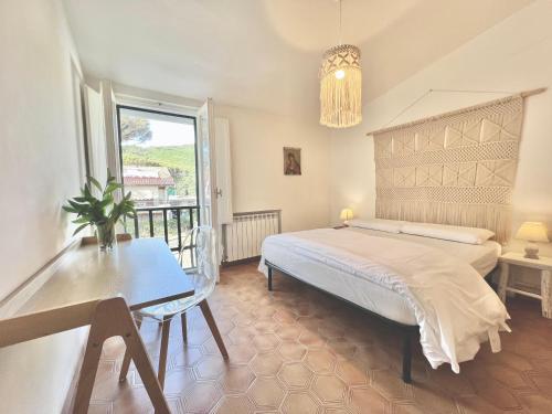 Un dormitorio con una cama y una mesa y una ventana. en Rosanna, terrazza vista mare, 2 camere, clima e 2 posti auto a soli 50 m dal mare! by Alfareal, en Castiglione della Pescaia