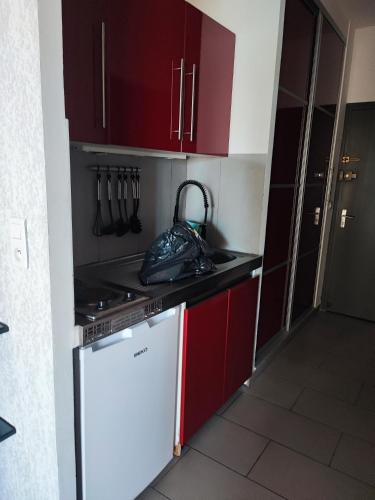une cuisine avec des armoires rouges et un réfrigérateur blanc dans l'établissement studio bord de mer, à Santa-Lucia-di-Moriani
