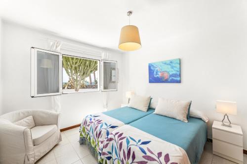 Un dormitorio con una cama y una silla y una ventana. en Casahost El Cable Seaview Beach house, en Arrecife