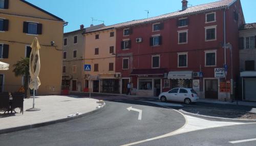 a street with buildings and a white car on the road at Apartment Nika in Umag
