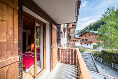 a balcony of a house with a bed and a window at La Flèche d'Or in Châtel