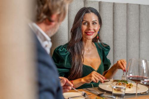 a woman in a green dress sitting at a table with a man at Boutique Hotel AMARIL in Castelbello-ciardes