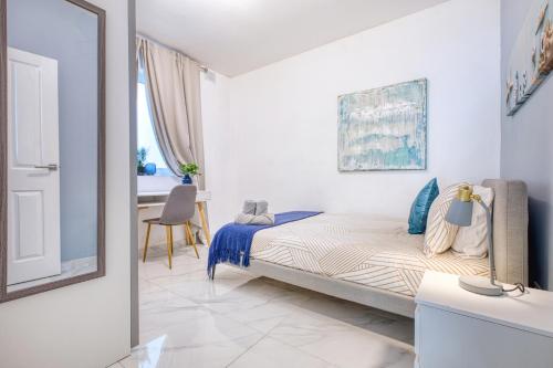 ein Schlafzimmer mit einem Bett, einem Tisch und einem Spiegel in der Unterkunft Bright spacious getaway close to the Sea in Gżira