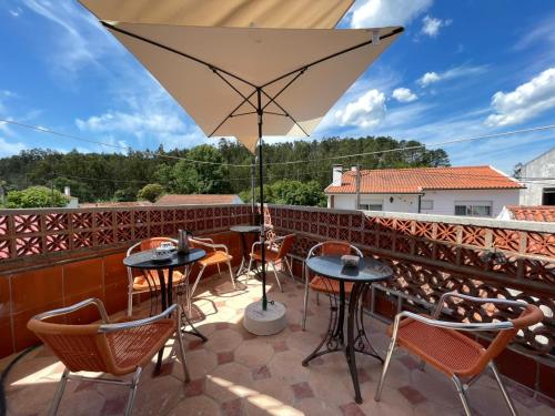 a patio with tables and chairs and an umbrella at Orange Tree house, Silver Coast, Alcobaça, Nazaré in Alpedriz