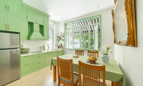a kitchen with green cabinets and a table with chairs at Éclectique Hanoi Homestay in Hanoi