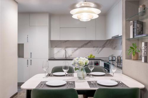 a white kitchen with a table with chairs and glasses at The Five Residences Hanoi in Hanoi