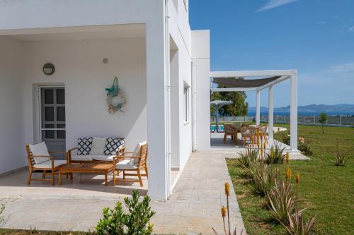 a white house with a patio with chairs and tables at Villa Miniera in Linopótis